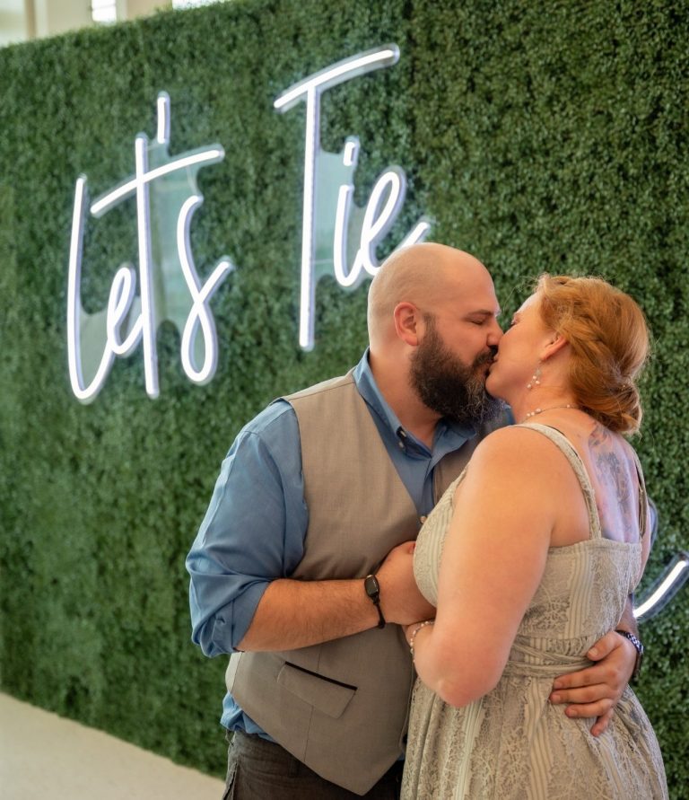 Bride & Groom Just tied the knot by Iris Ramil Wedding Officiant Virgin Cruises Couple sharing a kiss in front of a green wall at the Port of Miami - Virgin Cruise Lines
