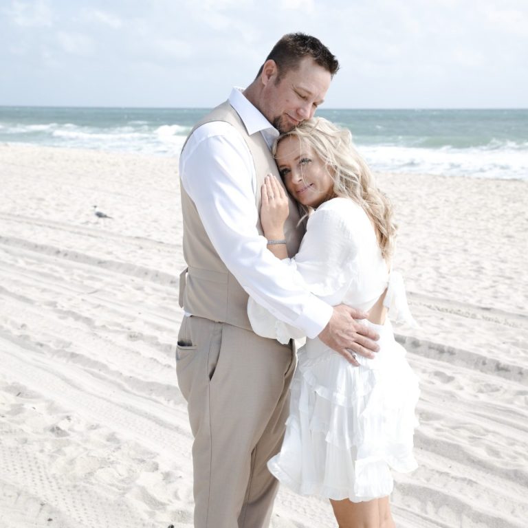 Bride & groom posing for Iris Ramil wedding photographer sitting on a bench A wedding couple poses together, smiling, with bridal bouquet in hand in Miami
