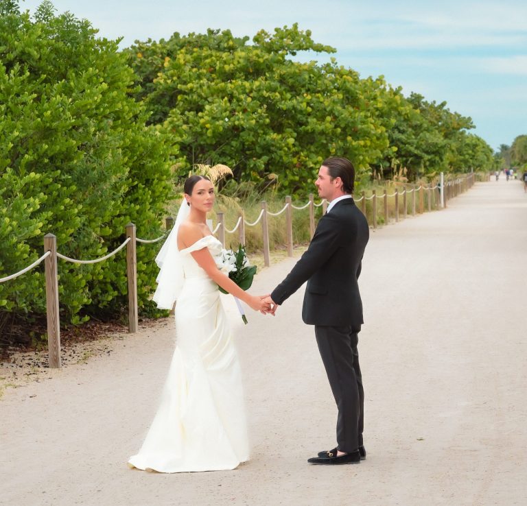 Just Married Couple in Miami Beach by Iris Ramil Bride & groom holding hands on a path in Miami Beach Florida.